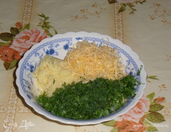 В чашку выкладываем отваренное пшено, половину натертого сыра, измельченный чеснок и зелень.