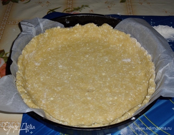 Достаем из морозильной камеры наше тесто. Раскатываем в виде лепешки. Выкладываем в форму, формируя бортики.