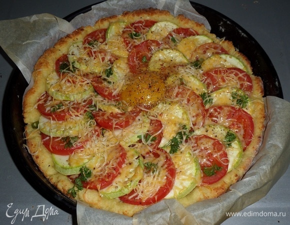 Достаем пирог из духовки. В центр пирога разбиваем свежее куриное яйцо. Добавляем соль и смесь перцев. Возвращаем пирог в духовку.