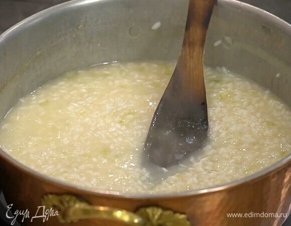 Разогреть в глубоком сотейнике 1 ст. ложку сливочного и оливковое масло и обжарить подготовленные овощи, всыпать рис и, постоянно помешивая, обжарить его до прозрачности, затем влить 100 мл вина, дать алкоголю выпариться и добавлять по одному половнику горячий бульон, так чтобы рис не плавал, но и не пригорал.