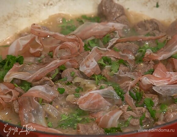 Когда мясо будет практически готово, посолить его, поперчить, посыпать чили и измельченной кинзой, добавить грудинку, накрыть крышкой и выключить огонь.