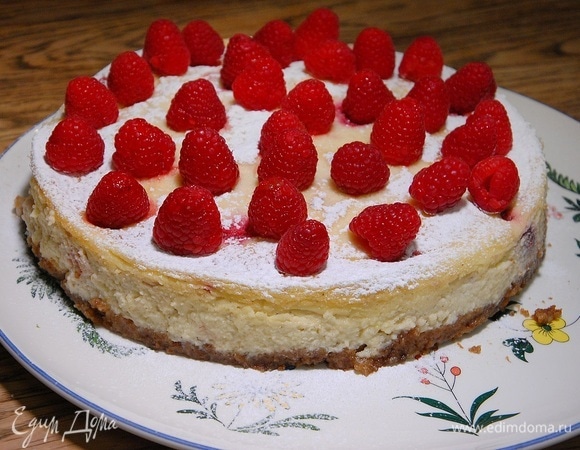 Готовый чизкейк остудить, затем вынуть из формы, посыпать сахарной пудрой и украсить оставшейся малиной.