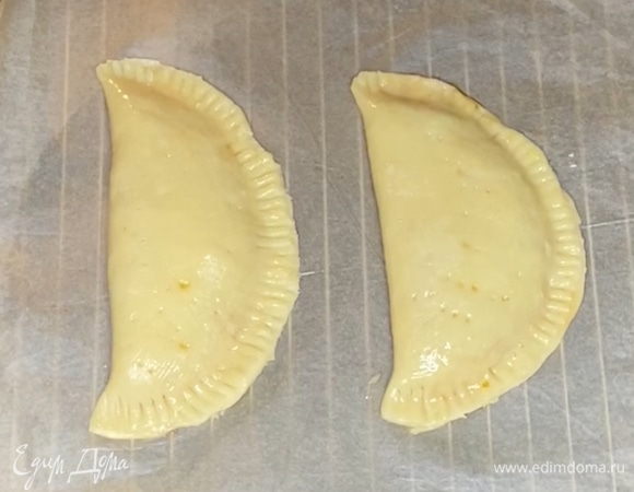 Когда начинка и тесто остынут, вырезать из теста два круга. Начинку выложить на 1/2 часть круга, накрыть второй частью и защипнуть края вилкой. Смазать желтком и убрать в разогретую духовку на 20–25 минут при 190°C. Готовить до румяности.