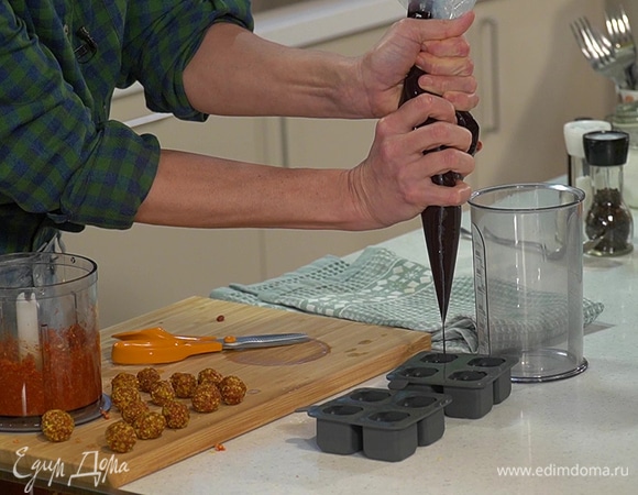 Силиконовую форму для конфет с помощью кондитерского мешка наполнить шоколадной массой на 2/3, поместить в каждое отделение по шарику начинки и заполнить доверху шоколадом.