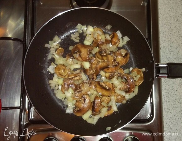 Шампиньоны разморозить и нарезать тонкими пластинами. Добавить шампиньоны на сковороду к луку. Перемешать и обжаривать еще около 8 минут.