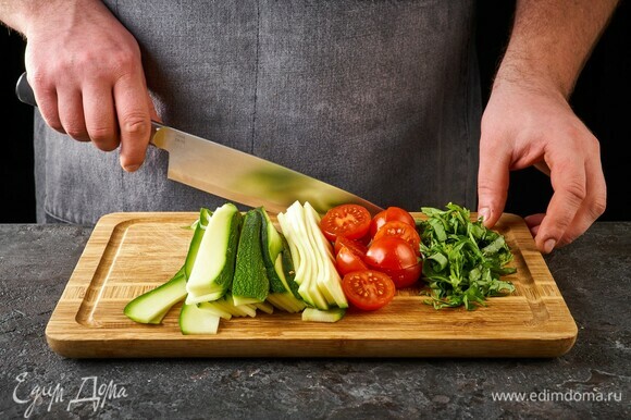 Теркой для корейской моркови или ножом для чистки овощей нарежьте цукини на тонкие длинные полоски. Черри разрежьте пополам, нарежьте крупно базилик.