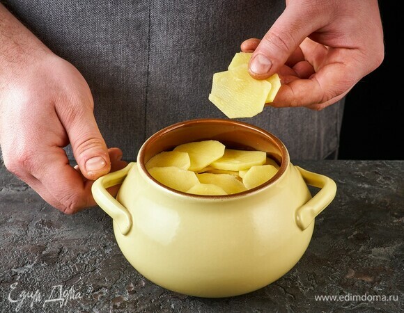 Верхним слоем выложите картофель. Накройте крышкой и поставьте в духовку, разогретую до 180°C, на 45 минут.