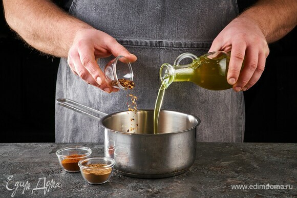 В кастрюлю с толстым дном влейте растительное масло. Добавьте паприку, молотый чили и корицу. Обжаривайте, помешивая.