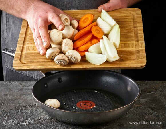 В глубокой сковороде обжарьте на растительном масле лук, морковь и грибы 5–7 минут.