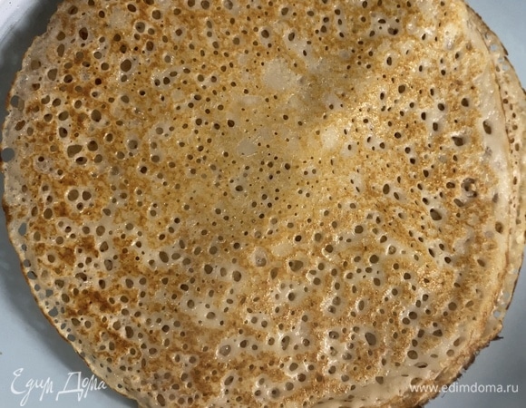 Приготовим блинчики. Разбить в чашу яйца, добавить немного соли. Взбить все до очень пышной пены. Затем медленной струйкой, продолжая взбивать, вливаем кипяток, далее, так же продолжая взбивать, добавляем медленно кефир. Теперь просеиваем в чашу муку и соду, продолжая взбивать. Муку просеивайте постепенно, не всю сразу, чтобы получить жидкое блинное тесто. Может понадобиться больше или меньше указанного количества. Дать тесту постоять минут 5–10, добавить растительное масло и выпекать на очень хорошо разогретой сковороде (это важно, если хотите такие же дырочки).