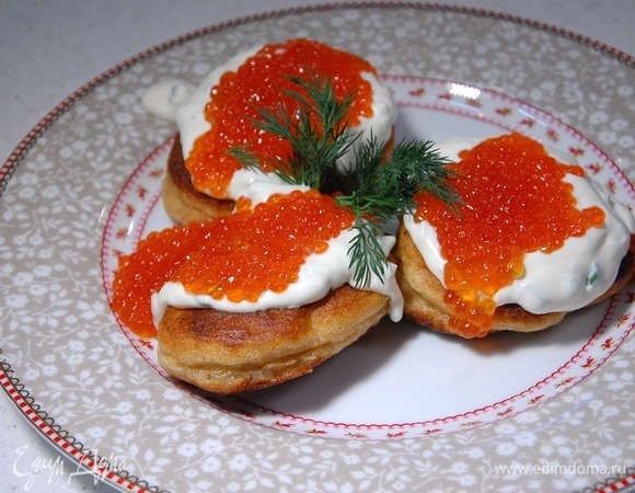 Подавать оладушки со взбитыми сливками и икрой, украсив укропом.