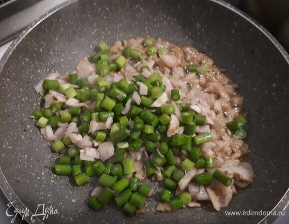 Затем добавьте галангал и чесночные стрелки и обжарьте пару минут.
