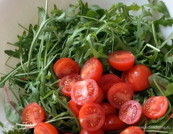 Томаты черри разрежьте пополам и добавьте к зелени.