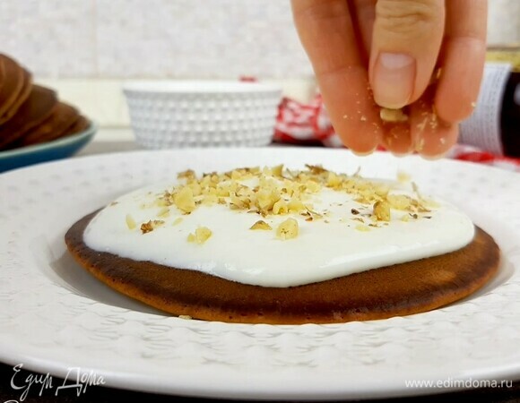 Остывшие панкейки собираем в виде тортика, промазывая кремов и посыпая орешками. Можно убрать его в холодильник минут на 30, чтобы крем стабилизировался и пропитал панкейки.