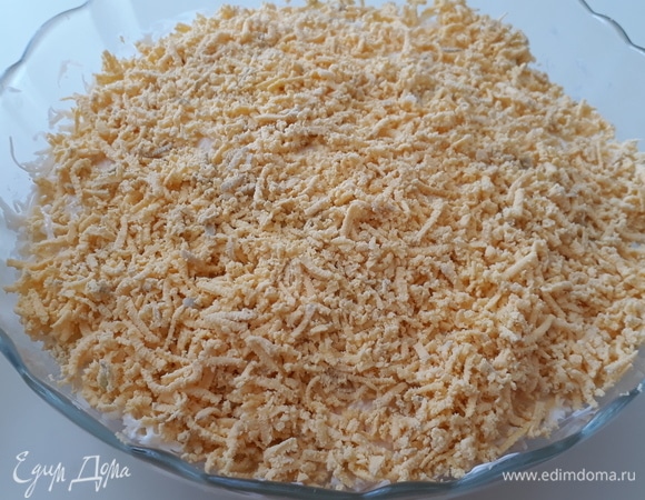 Верхним слоем натираем на мелкой терке яичные желтки и грецкие орехи. Салат готов!
