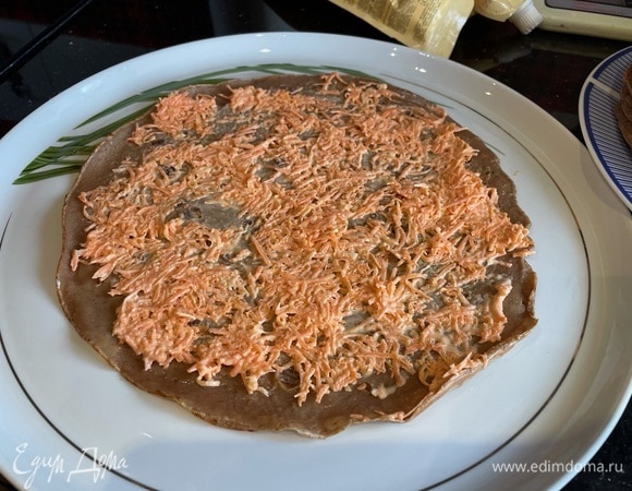 Соберите торт: на первый блин нанесите тонкий слой моркови с чесноком, сверху — второй блинчик. Чередуйте блинчики с начинкой, пока ингредиенты не закончатся.