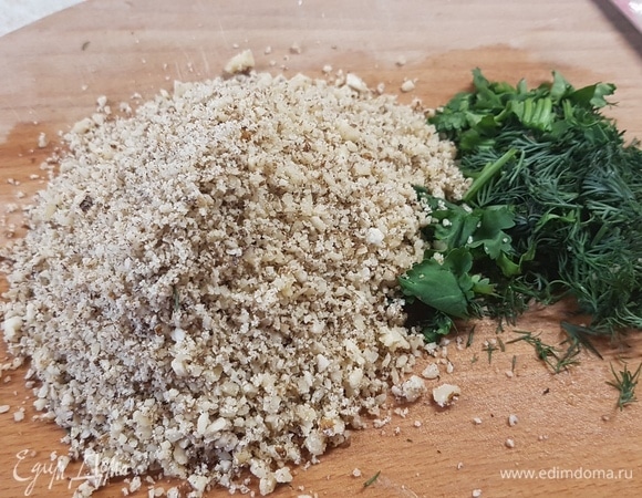 Грецкие орехи измельчить блендером. Любимую зелень мелко нарезать.