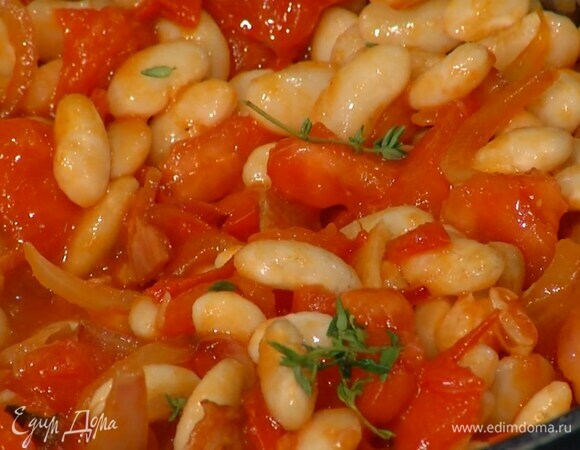 Помидоры нарезать небольшими кубиками, выложить в сковороду с луком и перемешать, затем добавить готовую фасоль, листья тимьяна, еще раз посолить и перемешать.