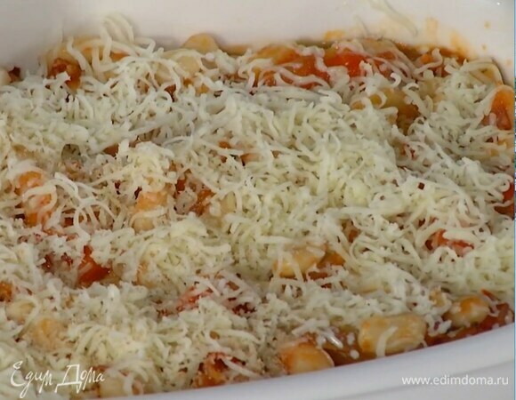 Жаропрочную керамическую форму смазать оставшимся оливковым маслом, равномерно выложить фасоль, посыпать сыром и сухарями и отправить в разогретую духовку на 20–25 минут.