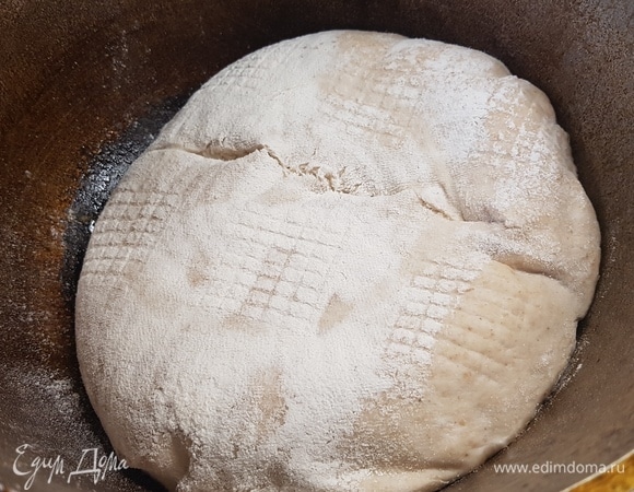 Выпекать хлеб надо в чугунке с крышкой. Для этого поставить чугунок в духовку, нагревать минут 30 при температуре 250°C. Как только чугунок нагрелся, быстро переложить хлеб, сделать надрез, накрыть крышкой и поставить выпекаться в духовку. Готовить 15 минут при 250°C, потом снизить до 200°C и выпекать еще 20 минут. Снять крышку и выпекать еще 5 минут.