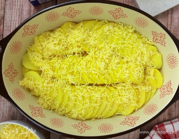 В форму выкладываем половину картофеля в качестве первого слоя. Посыпаем одной частью тертого сыра. Затем выкладываем второй слой картофеля и посыпаем оставшимся сыром.