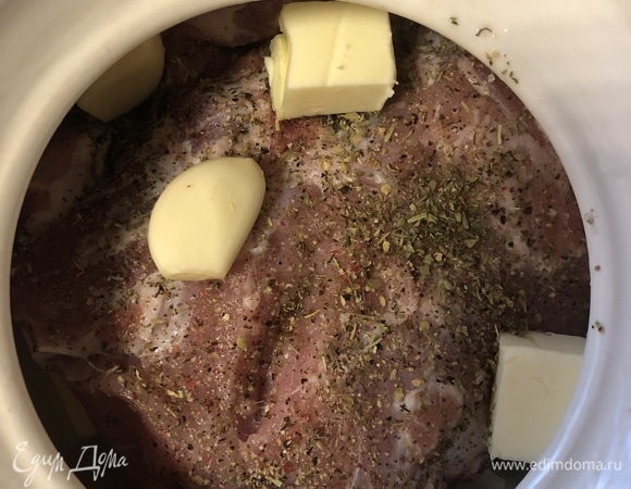 Кусок свинины вымыть, обтереть бумажными полотенцами и натереть солью, перцем и любимыми специями для мяса. Уложить мясо в горшок на кубики масла. Сверху выложить зубчики чеснока, оставшиеся кубики масла и листочки розмарина.
