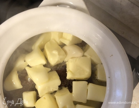 Поставить горшок сначала на сильный огонь, чтобы разогреть горшок, затем, когда масло начнет таять, перевести огонь на уровень ниже среднего, закрыть крышкой и томить на этом огне в течение 1,5 часов. Периодически нужно переворачивать кусочек мяса, поливать его кипящим ароматным маслом, продолжать томить под крышкой до готовности. Готовое мясо желательно еще 2–3 часа подержать в этом сливочном «сиропе», затем мягкие зубчики чеснока (по сути, они сварены в масле) растереть и обмазать ими кусок готовой свинины.