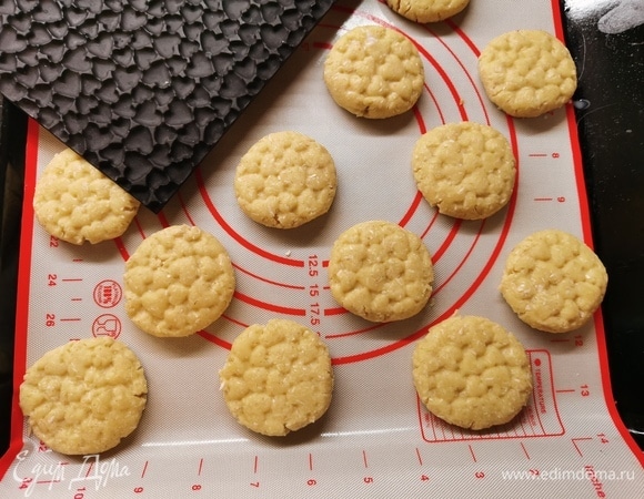 От теста отщипываем небольшой кусочек с грецкий орех (примерно 25–30 г), скатываем в шарик. Выкладываем на противень в шахматном порядке. Приплюснуть рукой наши шарики (или дном стакана, или вилкой). Мы решили сделать с помощью силиконового коврика, чтобы были красивые узоры.