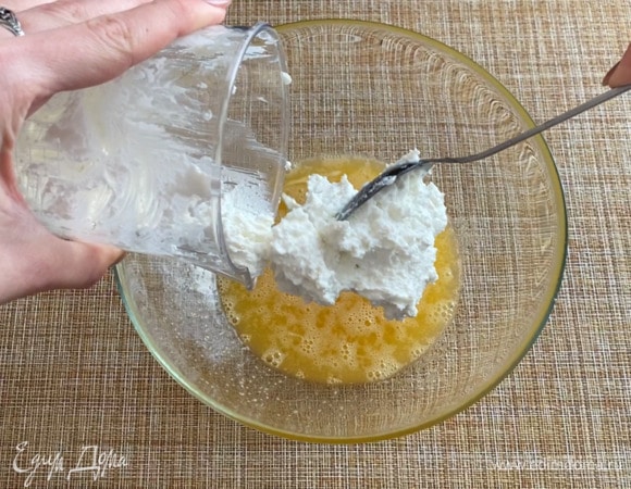 В глубокой чашке взбиваю два яйца с сахаром и солью. Добавляю творог и все тщательно перемешиваю.