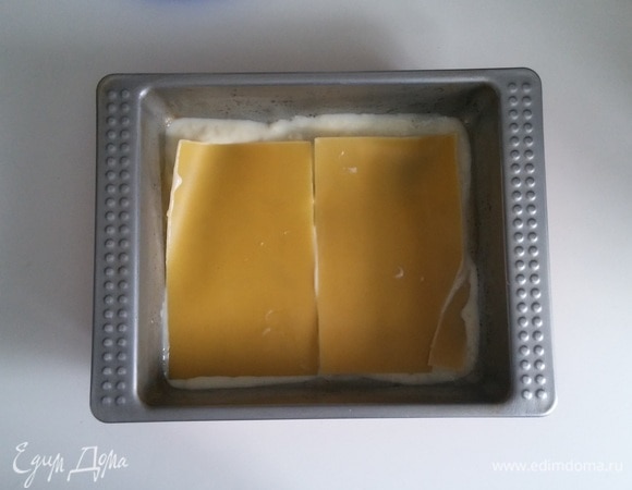 Берем форму, в которой будем запекать лазанью, и смазываем ее растительным маслом. Затем выкладываем на дно формы чуть-чуть соуса бешамель и поверх соуса — два листа теста для лазаньи (для нижнего слоя я использую только два листа теста для лазаньи).