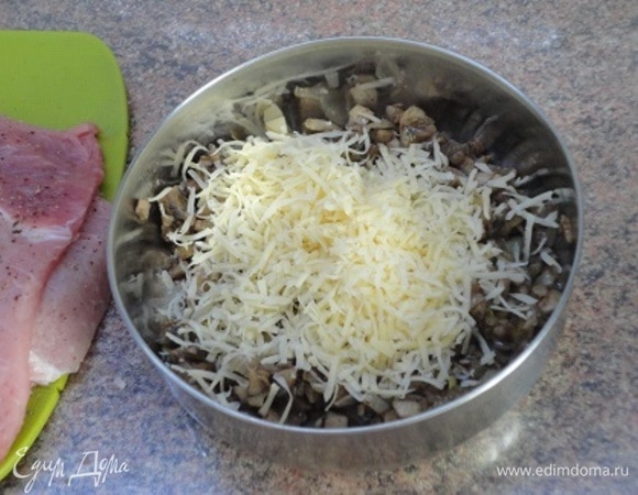 К остывшим грибам добавить натертый на мелкой терке сыр и перемешать.