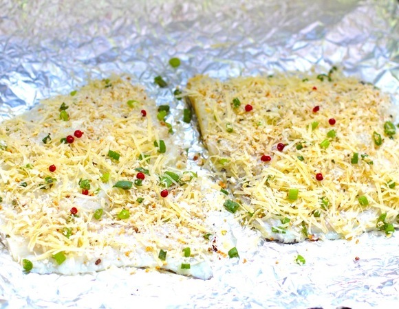 Обваляйте рыбу в панировочной смеси, выложите на противень. Полейте рыбу лимонным соком, посыпьте розовым перцем.