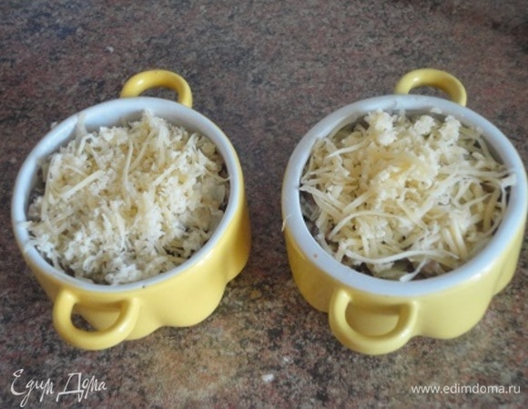 Сюда же в сковороду выложите грибы и перемешайте. Разложите по порционным формочкам и посыпьте тертым сыром.