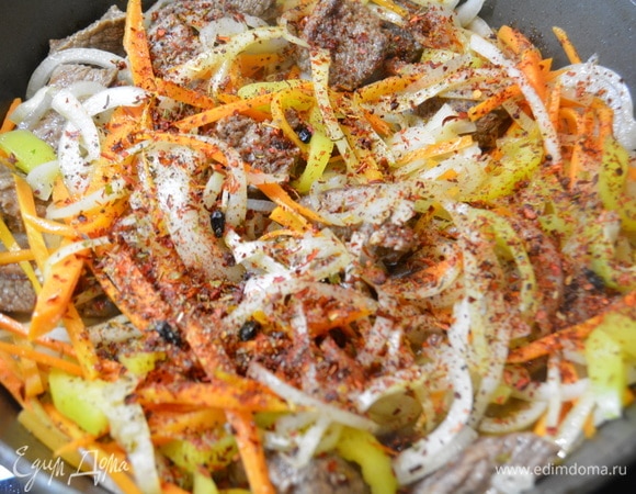 К мясу добавить нарезанные овощи: морковь, лук и перец. Добавить специи, соль, перец и жарить 8–10 минут, периодически помешивая.