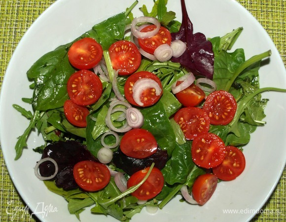 Выкладываем салат в глубокую тарелку. Небольшой лук-шалот нарезать кружочками. Помидоры черри разрезать пополам. Выкладываем лук и помидоры на салат.