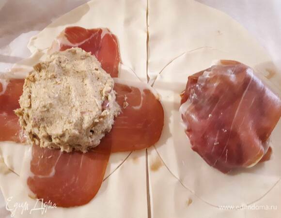 Разрежьте тесто на две части и вырежете два круга, которые будут в два раза больше по диаметру, чем вырезка. Положите две полоски ветчины крест-накрест. Смажьте вырезку пюре из артишоков, выложите на ветчину, заверните края и оберните еще одной полоской ветчины. Затем защипите края теста и смажьте взбитым яйцом.