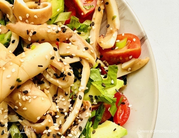 Теплых кальмаров отправляем к овощам, добавляем остатки соуса и посыпаем кунжутом.