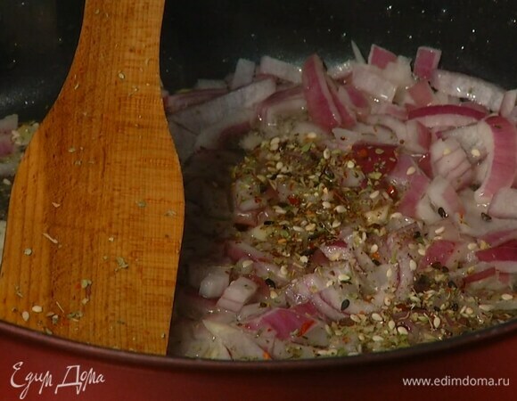 В глубокой сковороде разогреть оливковое масло и обжарить лук с чесноком, затем добавить кунжут, орегано, тимьян, майоран, сладкую паприку и чили, все посолить, перемешать и прогревать на небольшом огне.