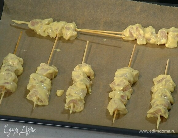 Нанизать замаринованное мясо на шпажки и выложить на противень, выстеленный бумагой для выпечки.