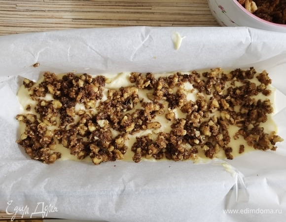 Прямоугольную форму застелить пекарской бумагой. Выложить 1/3 теста в форму, разровнять. На нее — 1/3 часть ореховой прослойки. Затем — снова тесто, прослойка, тесто. Сверху посыпать оставшейся прослойкой. Выпекать при 160°C 70 минут.