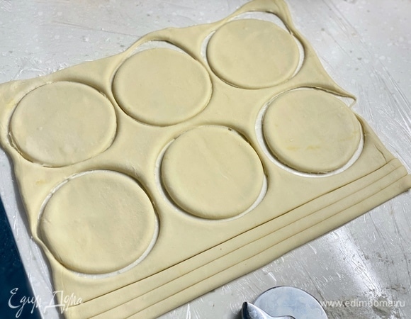 Слоеное тесто немного раскатать. Вырезать круги диаметром 7 см. Из остатков вырезать одинаковые полоски.