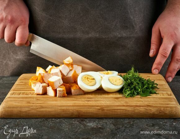 Копченую курицу нарежьте средним кубиком. Яйца — пополам. Зелень нарубите.