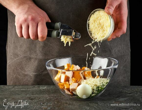 Выложите в салатник. Добавьте тертый сыр и выдавите чеснок.