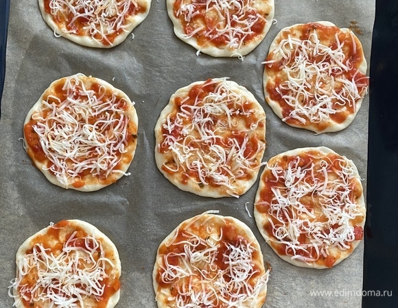 Подошедшее тесто обмять, разделить на 8 равных частей. Духовку разогреть до 215°C. Противень застелить пергаментом, каждому кусочку придать округлую форму диаметром 8–9 см.