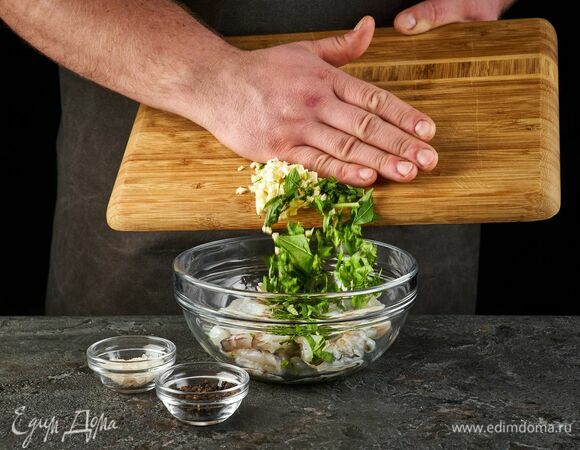 Выложите в глубокую чашу креветки, зелень и чеснок. Посолите, поперчите, перемешайте.