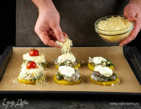 Затем выложите майонез и посыпьте тертым сыром. Украсьте помидорами и запекайте в духовке при 180°C около 10 минут.
