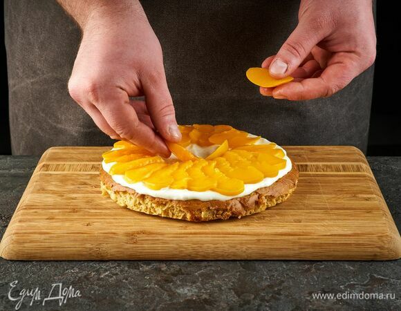 Соберите торт. Корж смажьте кремом, разложите персики.