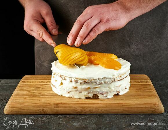 Накройте вторым коржом. Верх торта и бока смажьте кремом. Украсьте половинками персиков. Уберите в холодильник на 5–6 часов или на ночь.