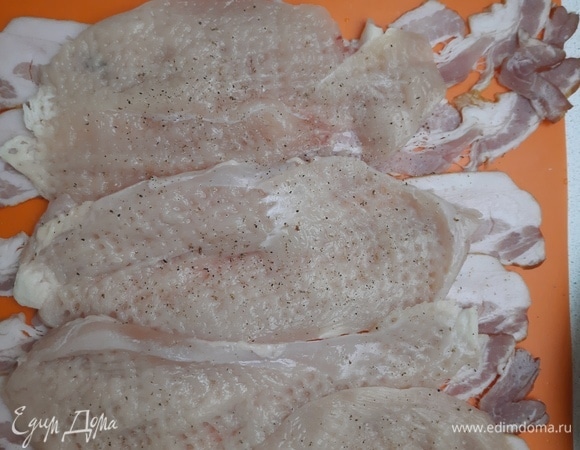 Филе курицы нарезать и отбить. Разложить бекон (на мягкую доску или коврик, чтобы удобно было скрутить) и сверху выложить отбитое филе, посолить, поперчить.
