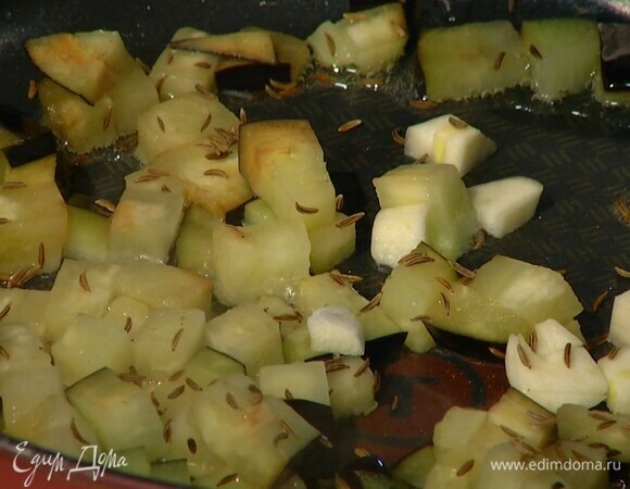 Разогреть в сковороде оливковое масло, выложить в нее нарезанный баклажан и чеснок, посыпать все тмином и перемешать.